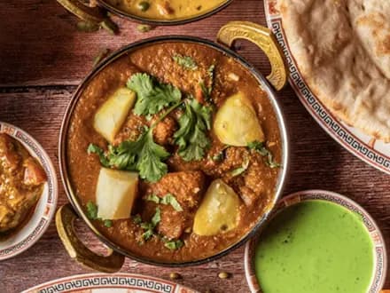A curry in a karahi, with naan and chutney